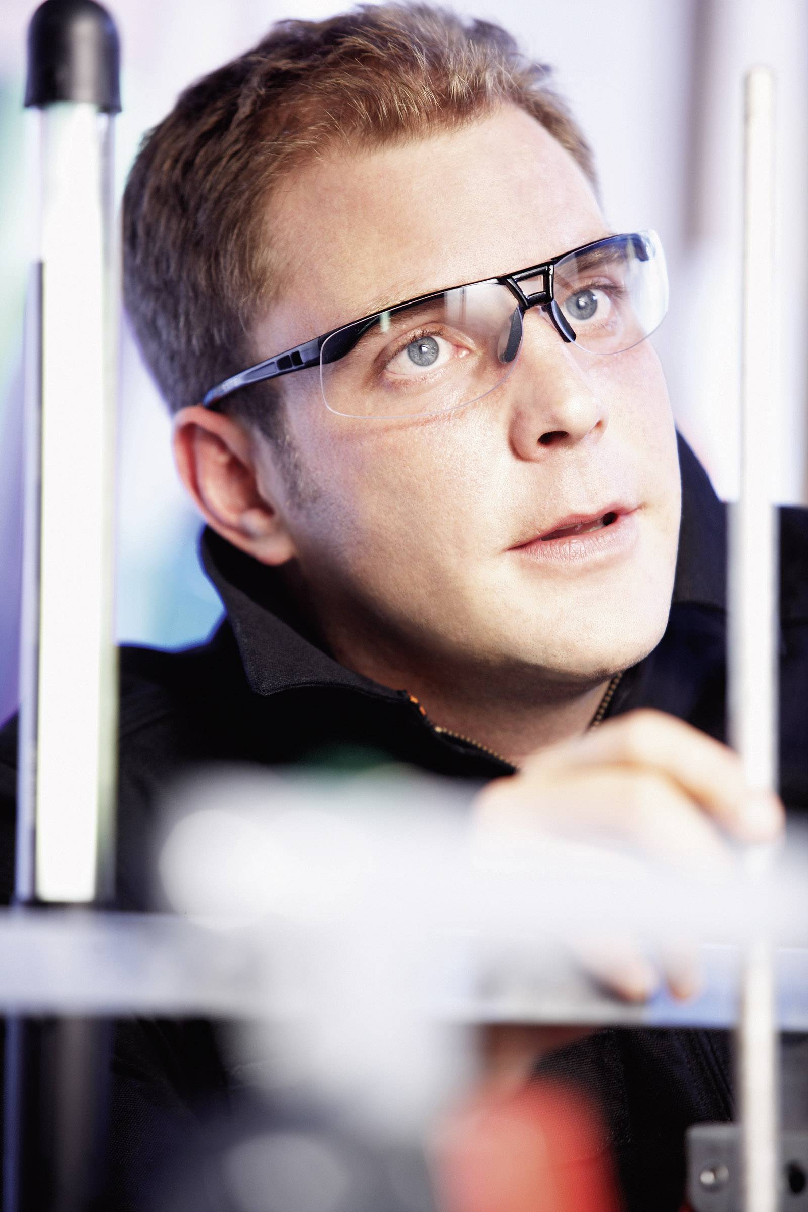 Ein Mann mit Schutzbrille konzentriert sich auf technische Arbeiten, möglicherweise in einem Labor oder einer Werkstattumgebung.