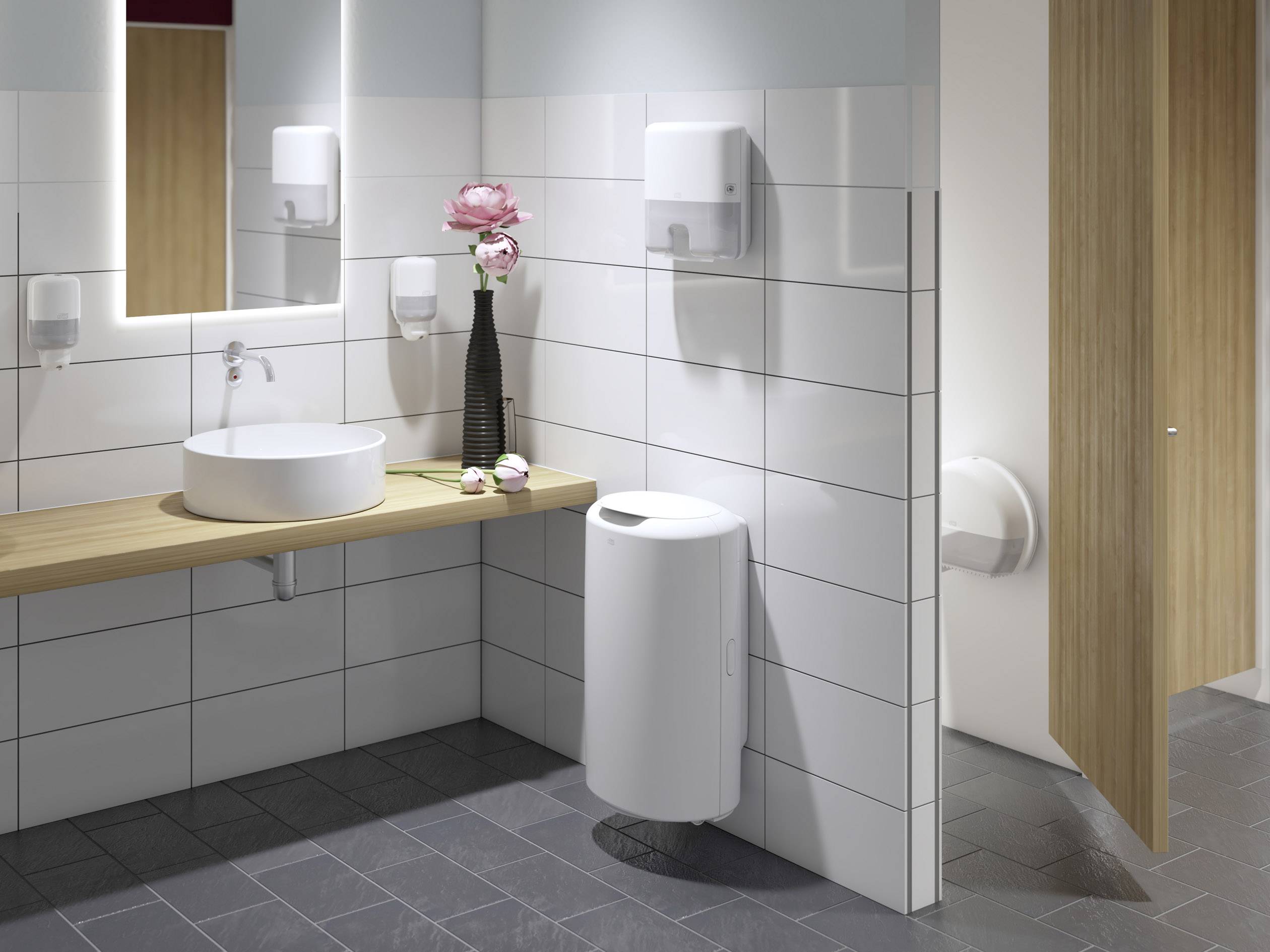 Modernes Badezimmer mit Waschbecken, Spiegel, Handtuchspender und Vase mit rosa Blume auf Holzablage. Tür zum WC teilweise geöffnet.