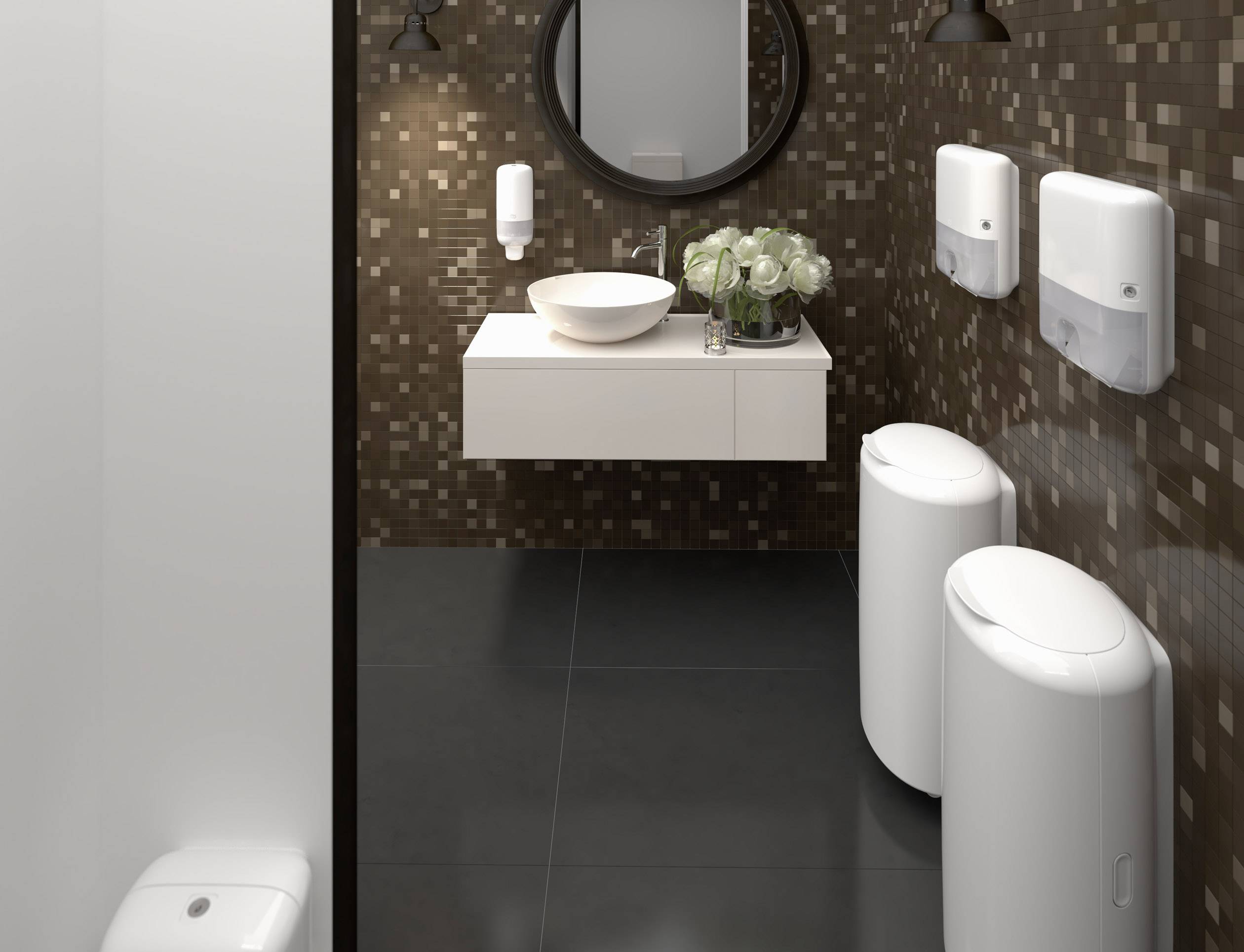 Ein elegantes Badezimmer mit dunklen Fliesen und einem runden Spiegel. Ein weißes Waschbecken mit Blumenarrangement steht auf einem schwebenden Schrank.