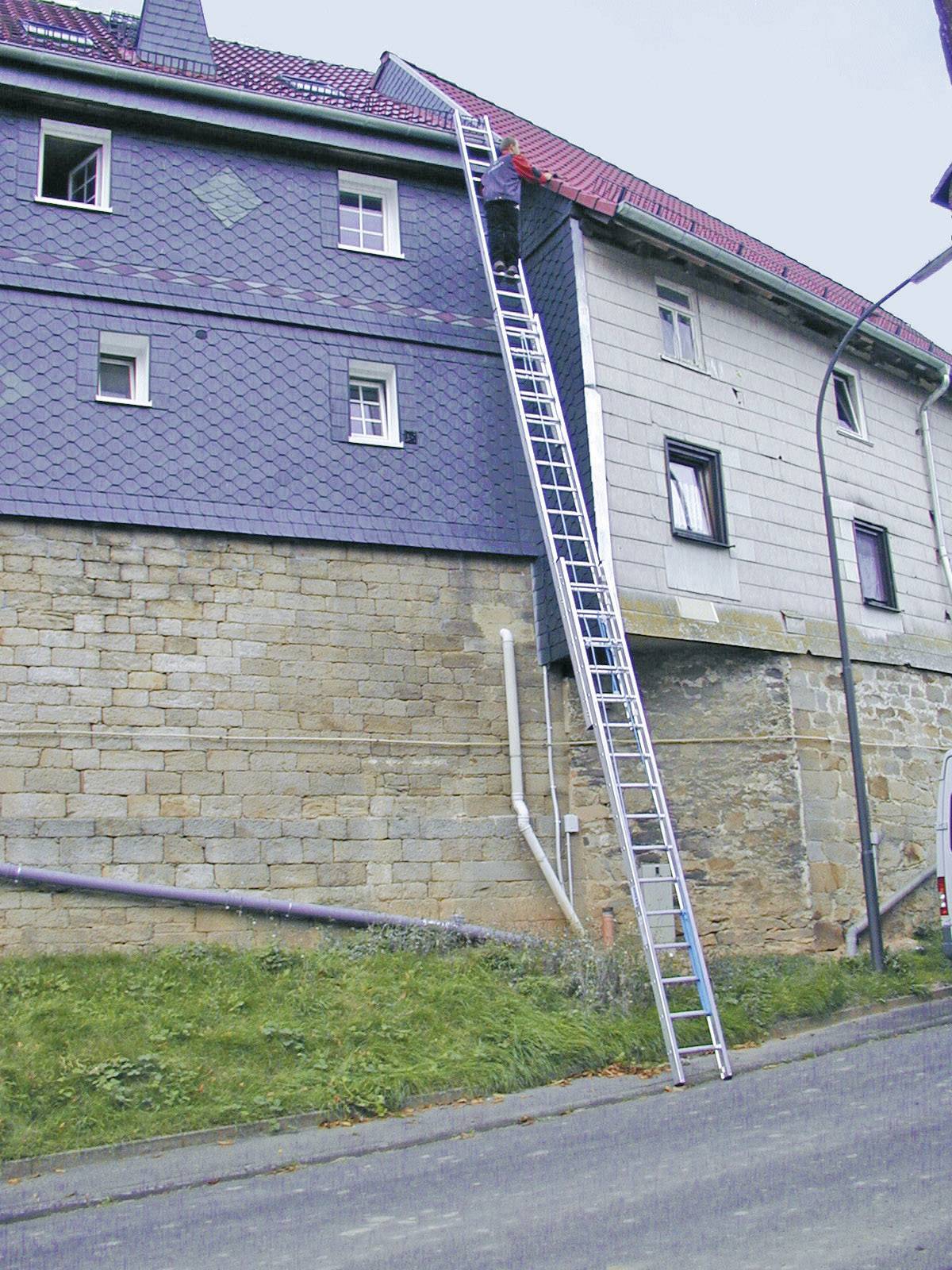 Langleiter führt an steiler Hauswand hinauf.