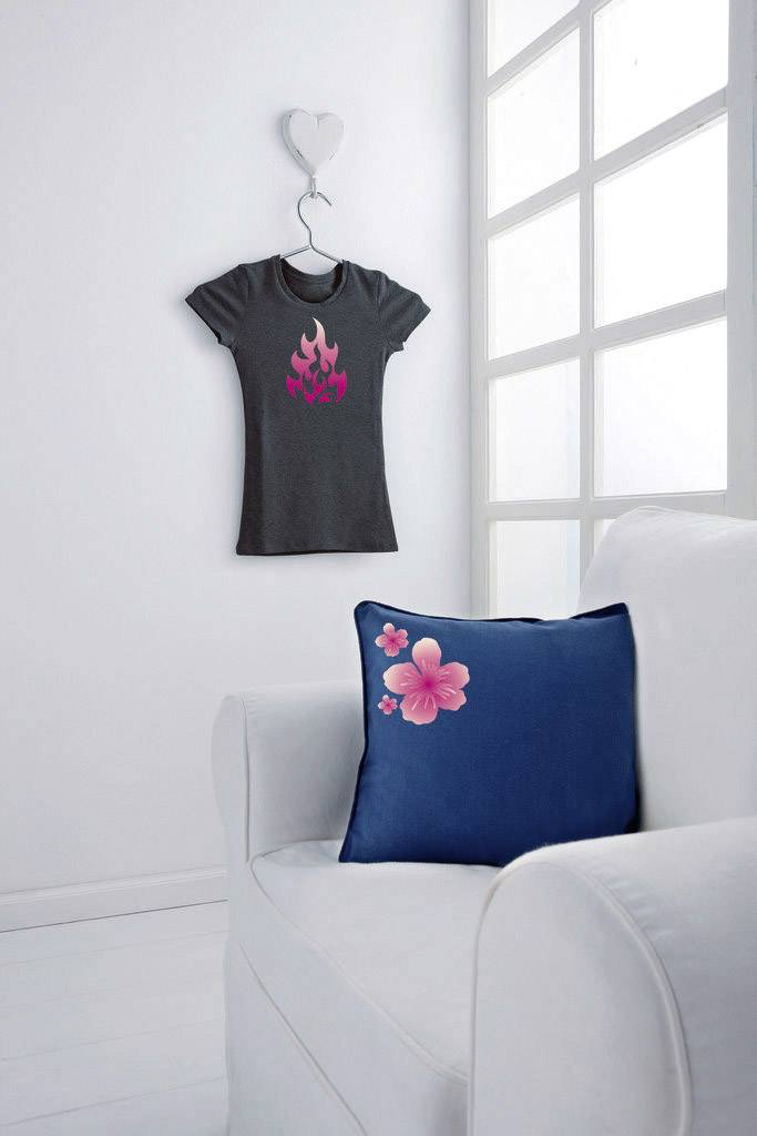 Ein dunkles T-Shirt mit einem Flammenmuster hängt an der Wand. Ein weißes Sofa darunter hat ein blaues Kissen mit rosa Blume.