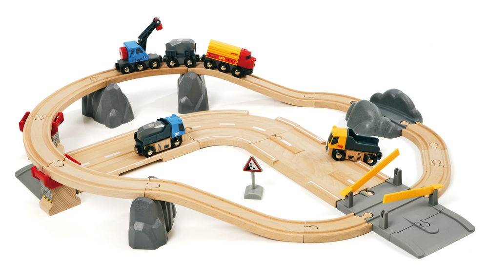 Holzspielzeugzug mit erhöhten Gleisen, kleinen Lastwagen und Baufahrzeugen auf Schleifenkurven und einem grauen Brückenabschnitt.
