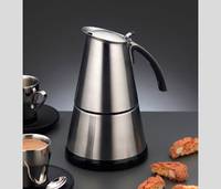 Edelstahlkaffeemaschine für die Herdplatte mit schwarzem Griff auf einer dunklen Oberfläche, gezeigt mit kleinen Tassen und Biscotti.