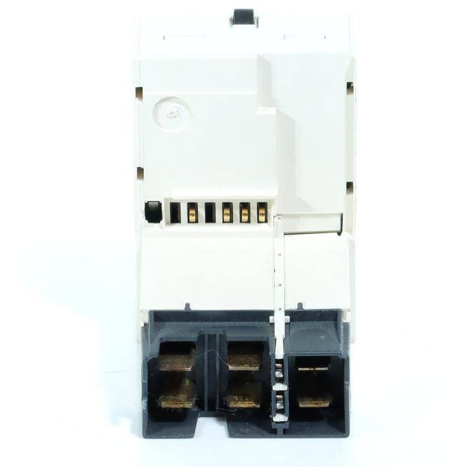 Nahaufnahme eines weißen elektrischen Steckers oder Relaiskomponenten mit schwarzen Anschlussöffnungen und Metallkontakten, shown gegen einen einfachen Hintergrund.