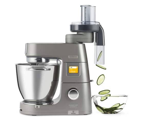 Silberner Standmixer mit Aufsatz, der Gurken in eine Schüssel schneidet und zeigt die Verwendung bei der Lebensmittelverarbeitung.