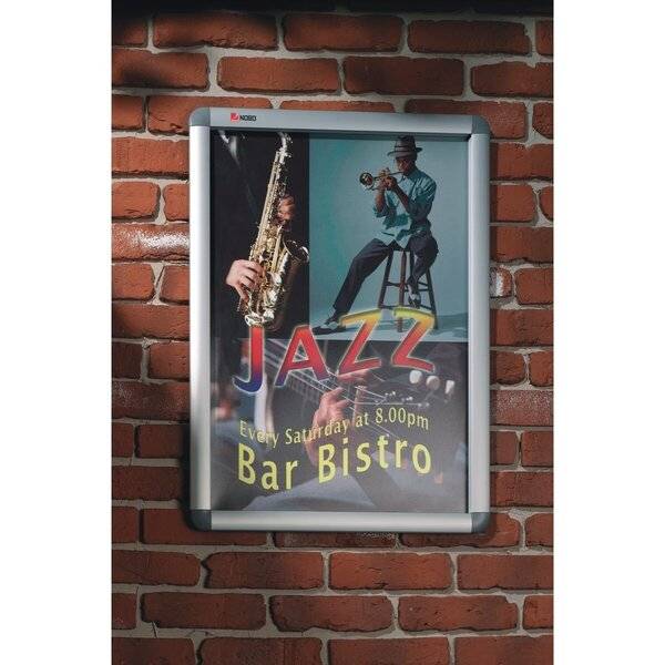 Gerahmtes Plakat an einer Backsteinwand, das Jazz in einer Bar-Bistro bewirbt, mit Saxophon- und Trompetenspieler und dem Text „Jeden Samstag um 20:00 Uhr