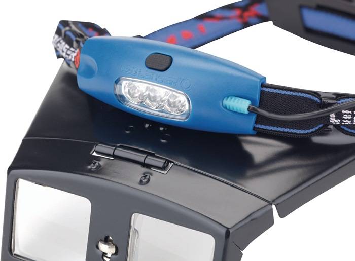Eine blaue Stirnlampe mit einem verstellbaren Riemen und drei LED-Lampen ist an einer schwarzen Kamera oder einem VR-Gerät befestigt, was auf Vielseitigkeit hinweist.