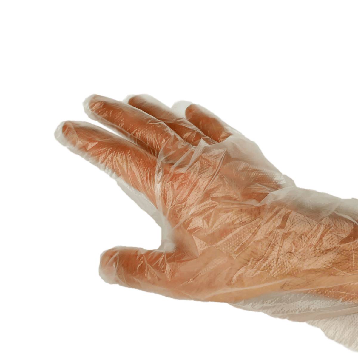 Nahaufnahme einer Hand, die einen transparenten, wegwerfbaren Kunststoffhandschuh vor einem schwarzen Hintergrund trägt.