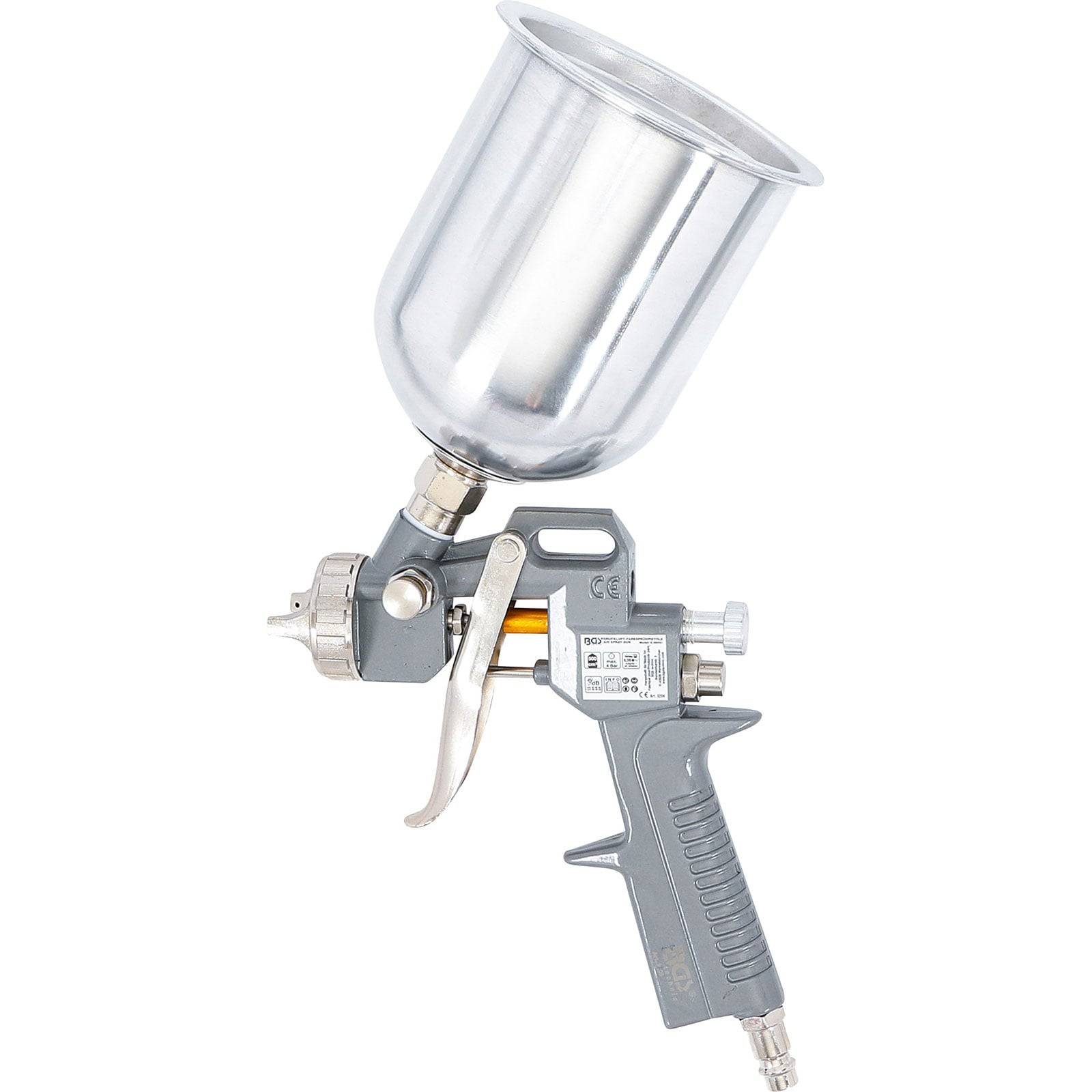 Eine silberne Sprühpistole mit einem Abzug und einem angeschlossenen Metallfarbbehälter wird vor einem weißen Hintergrund isoliert dargestellt.