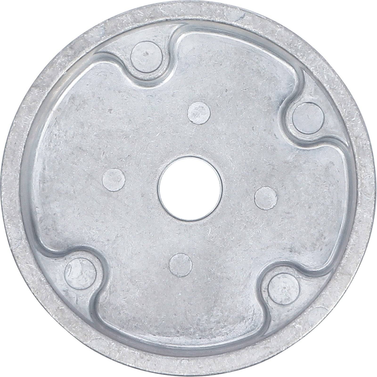 Eine runde, metallische Scheibe mit einem zentralen Loch und vier kleineren kreisförmigen Vertiefungen, die gleichmäßig um den Umfang verteilt sind.