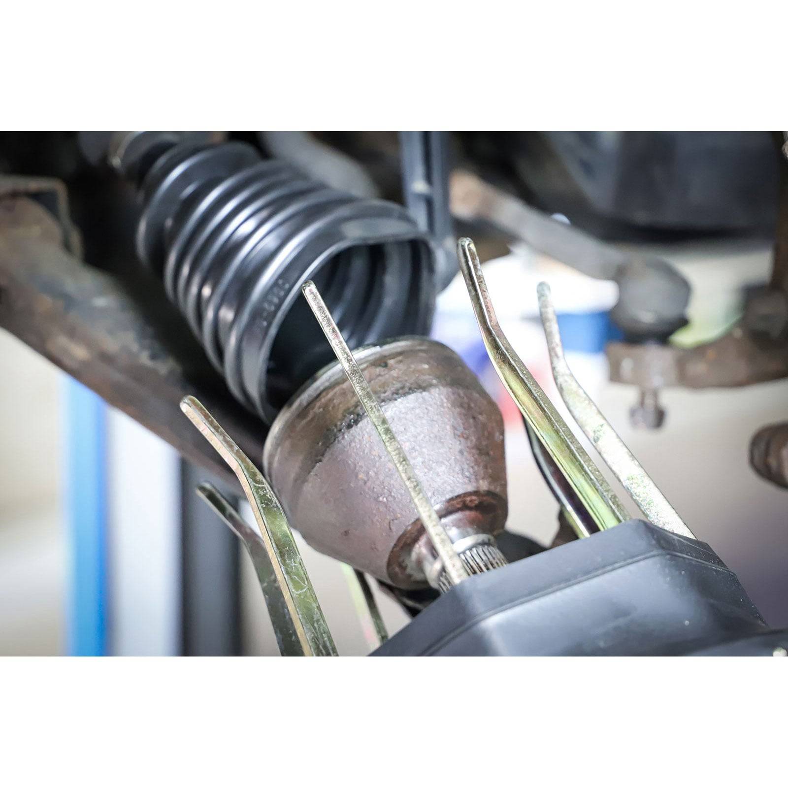 Eine Antriebswelle (Kardanwelle) wird in einer Werkstatt mit Hebewerkzeugen ausgebaut.