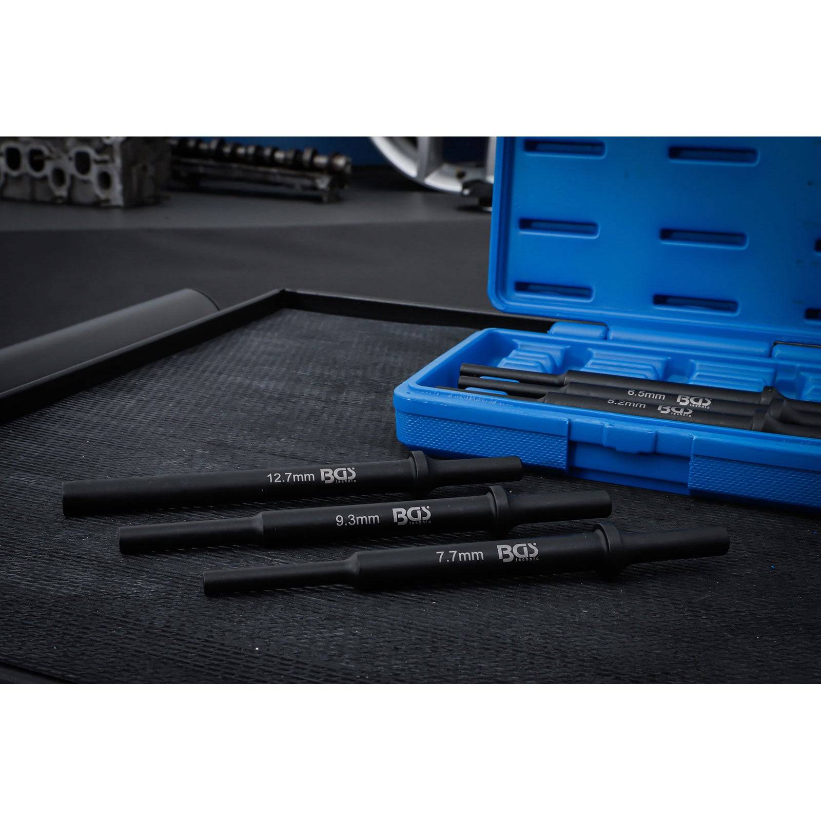 Ein Set schwarzer Präzisionswerkzeuge in den Größen 7,7 mm, 9,3 mm und 12,7 mm wird auf einer schwarzen Matte mit einem geöffneten blauen Transportkoffer präsentiert.