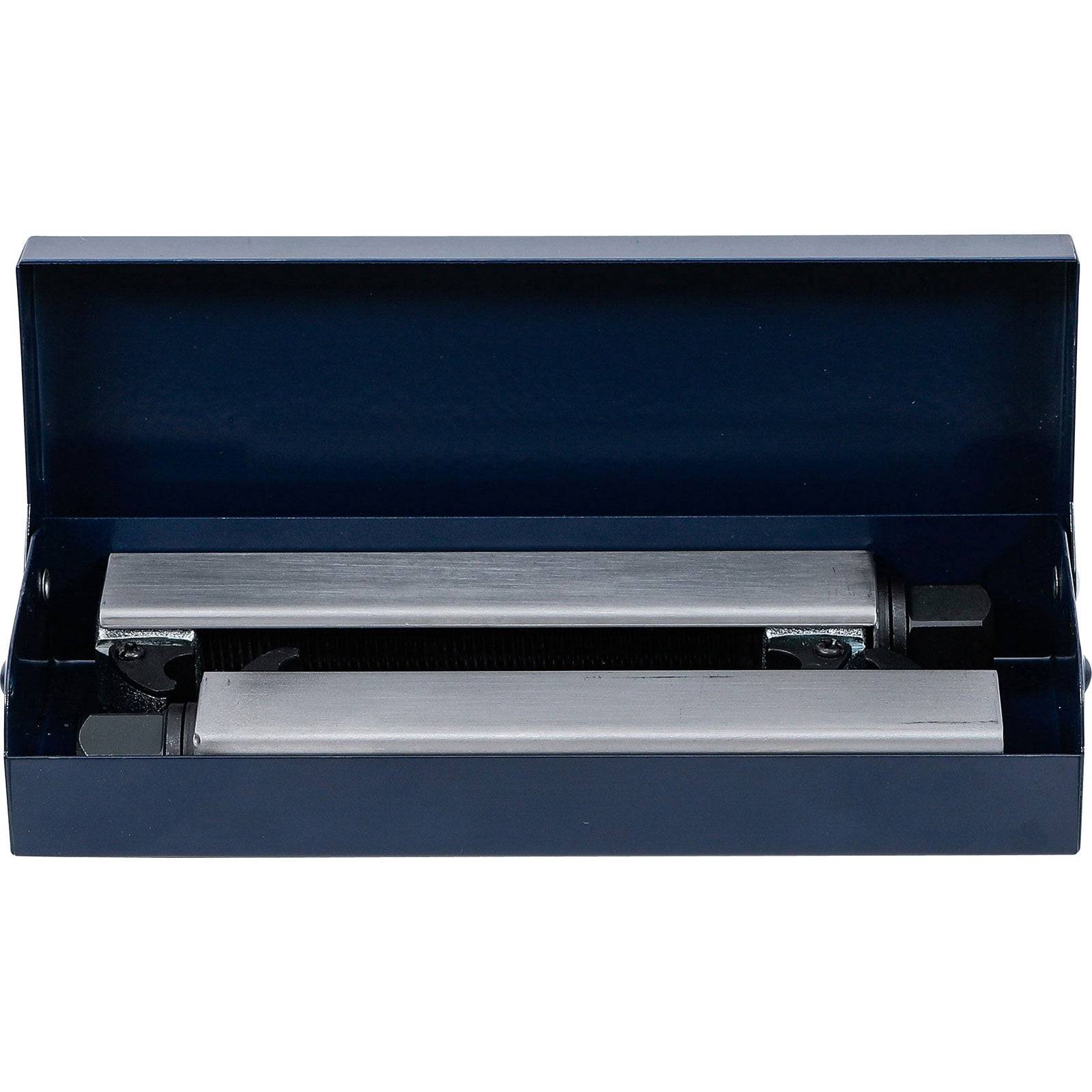 Eine geöffnete Schachtel, die zwei Schleifhilfen aus Metall enthält, die zur Werkzeugschärfung verwendet werden, vor einem einfarbigen Hintergrund.