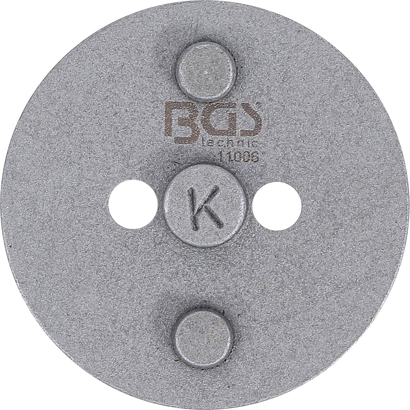Rundes, metallisches Ausrichtungswerkzeug mit drei erhöhten zylindrischen Punkten und zwei kreisrunden Löchern, mit der Marke 'BGS' und einem 'K' in der Mitte.