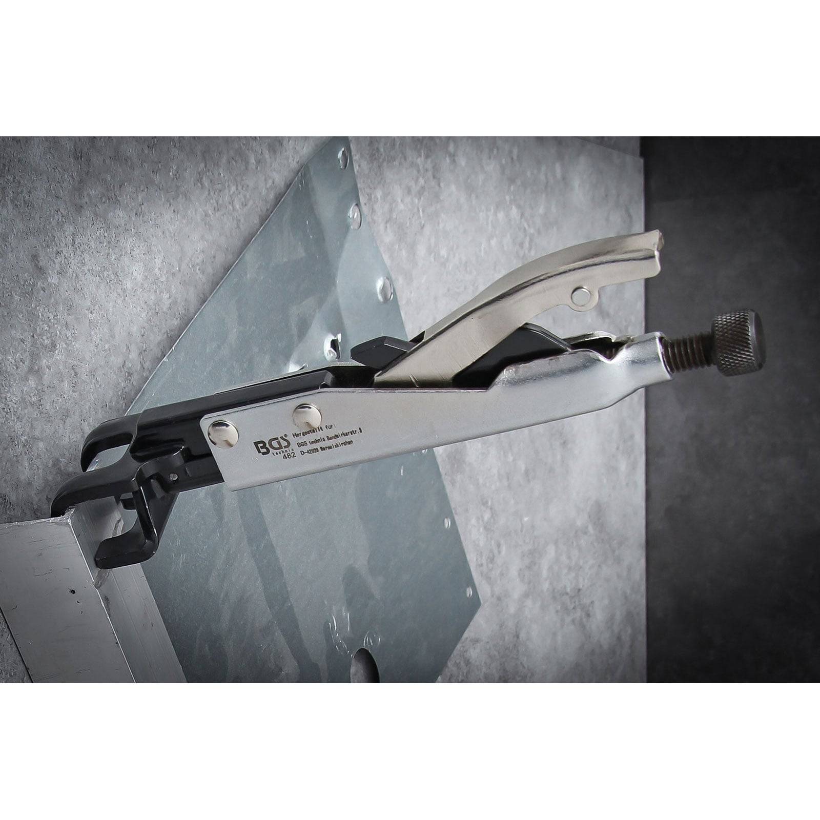 Eine metallische Klemmvorrichtung ist an einem Metallblech befestigt und richtet einen verbogenen Rand aus. Die Marke und Seriennummer des Werkzeugs sind an seiner Seite eingraviert.