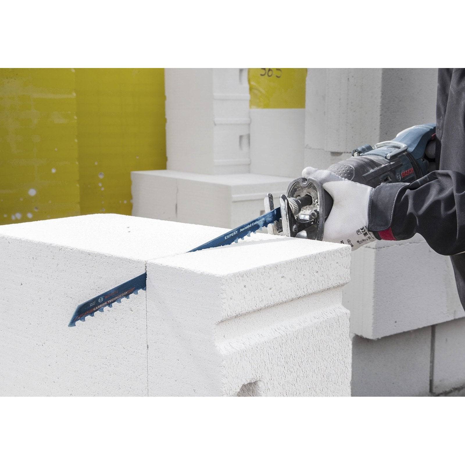 Eine Person schneidet einen weißen, leichten Betonblock mit einer handgeführten Kreissäge und legt dabei Wert auf Präzision bei der Bauausführung.