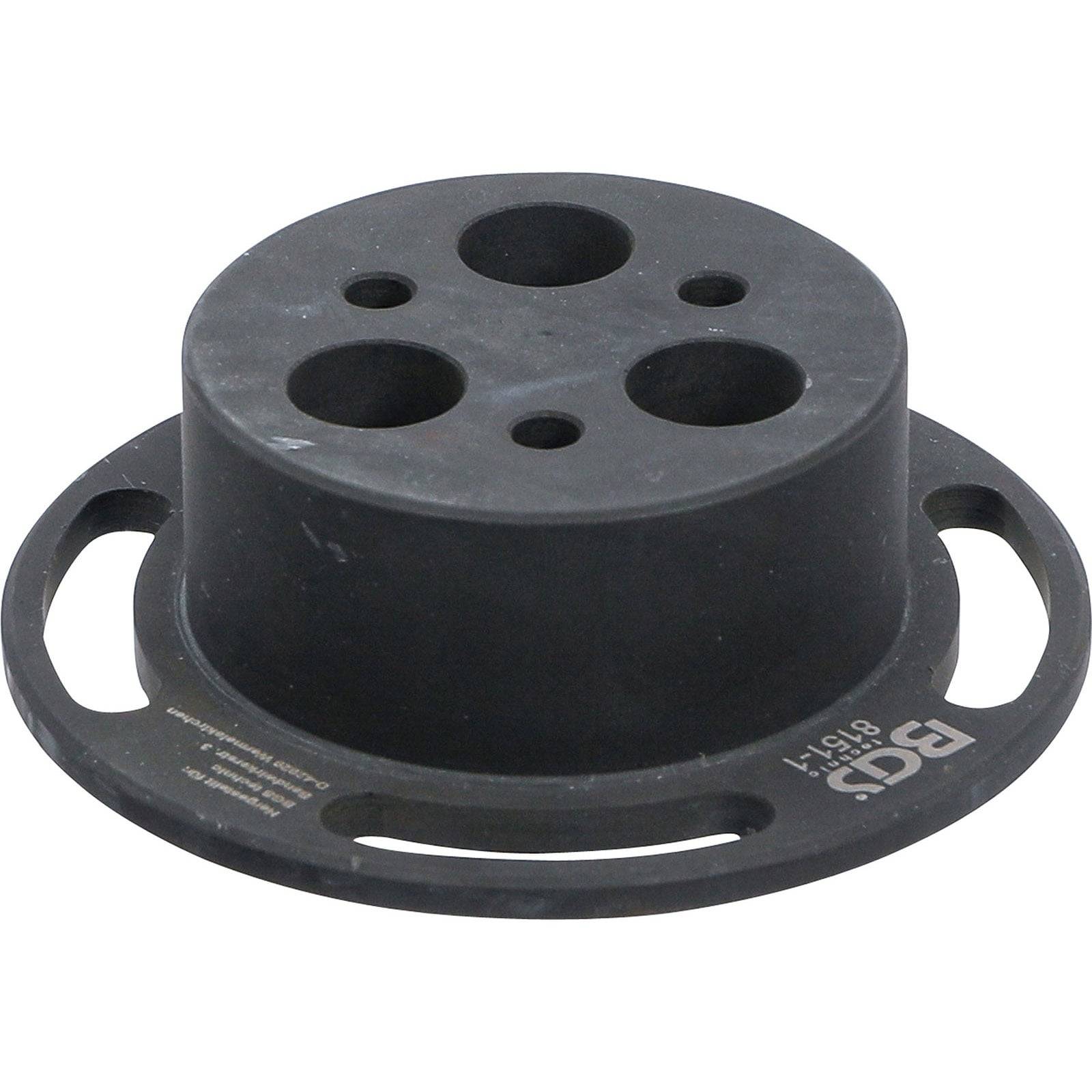 Ein schwarzes, rundes Gummipad mit vier Löchern, das als Schutz oder Unterstützung verwendet wird und mit der Aufschrift 'BGI 81515' an der Seite versehen ist.