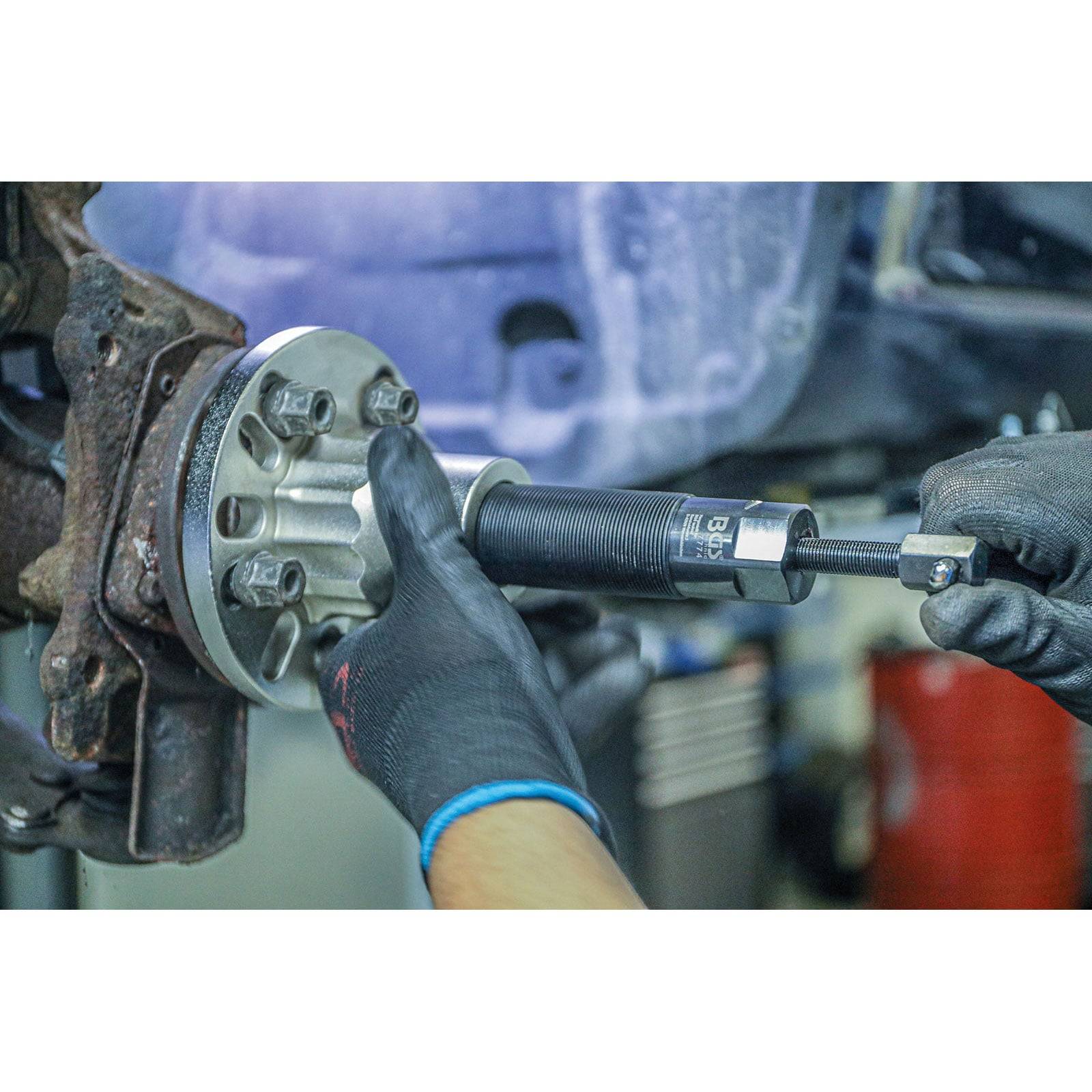 Ein Mechaniker nutzt ein Werkzeug, um Bolzen an einer Autoradnabe festzuziehen und zeigt damit Arbeiten zur Autoreparatur.