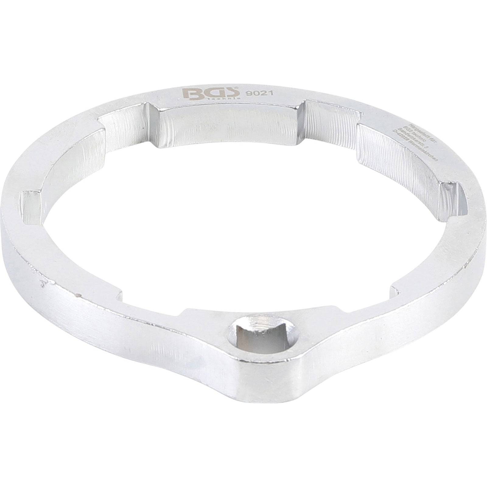 Ein silberner Ringschlüssel mit mehreren Kerben an seinem Rand, der für spezifische Reparaturaufgaben verwendet wird und einen quadratischen Sockel in der Mitte aufweist.