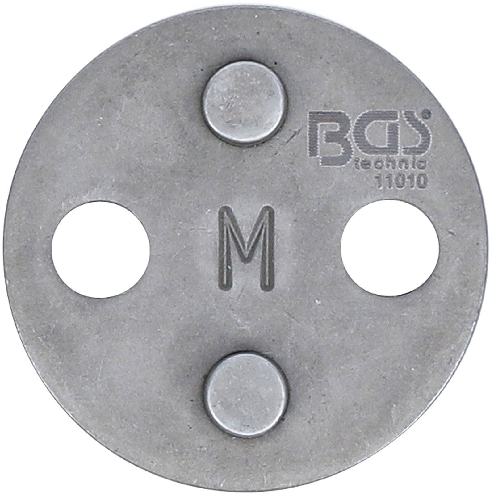 Ein Metallkreiswerkzeug mit der Beschriftung 'BGS technic 11010', das drei Ausschnitte und ein 'M' in der Mitte aufweist, wahrscheinlich für Autoreparaturzwecke verwendet.