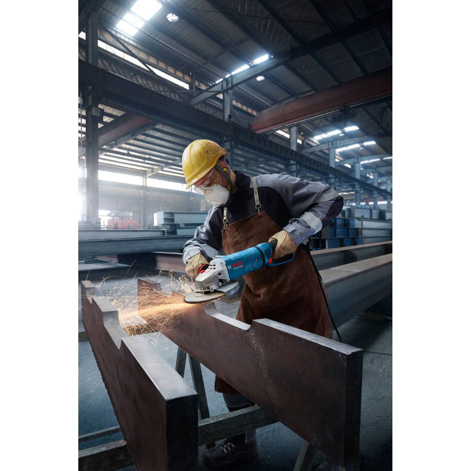 Ein Arbeiter in einer Fabrik trägt Sicherheitsausrüstung, während er ein Elektrowerkzeug verwendet, um einen großen Metallträger zu schneiden, wobei Funken während der Aktion umherfliegen.