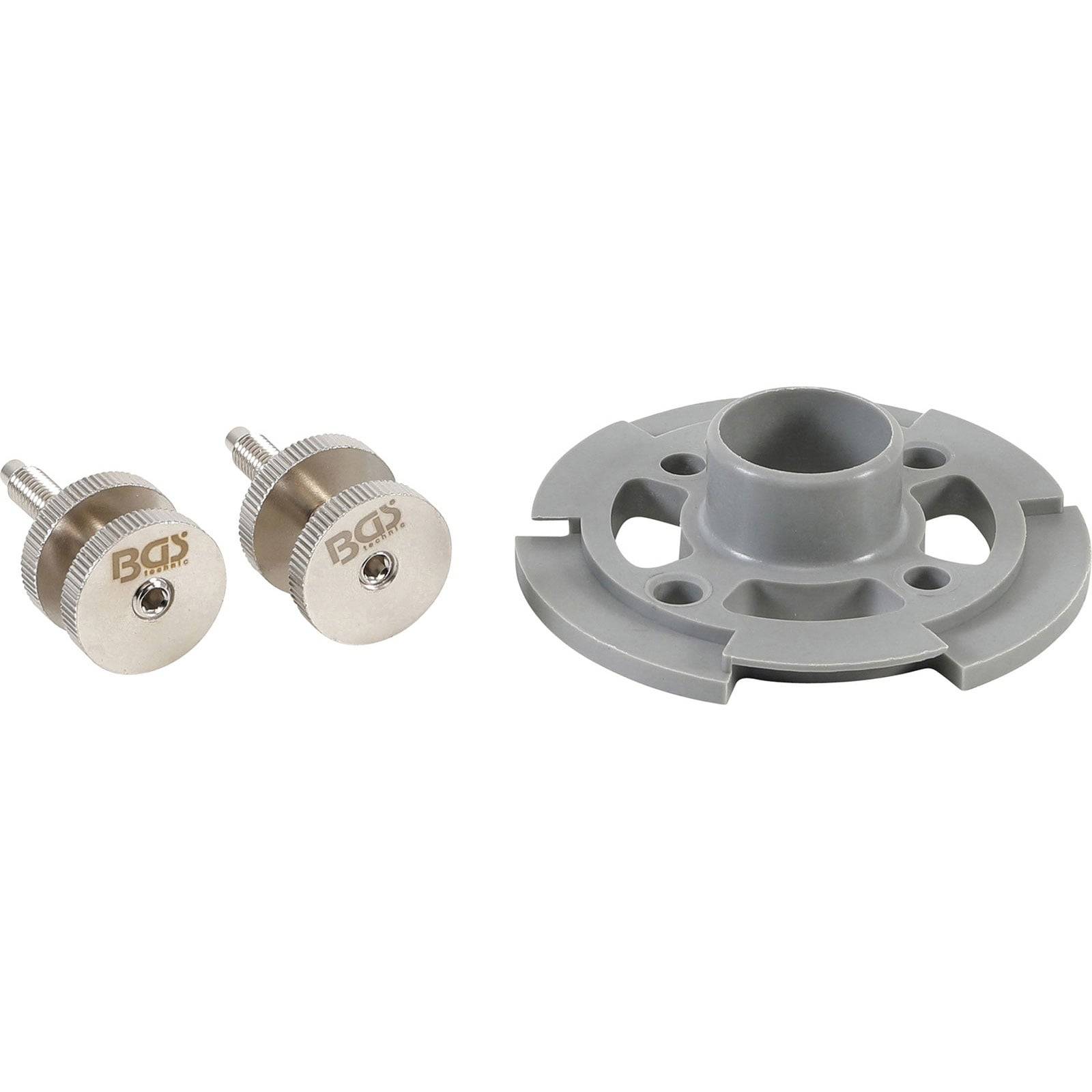 Ein Satz aus zwei Metallschrauben und einem grauen Kunststoffbauteil, möglicherweise zur Montage oder zum Zusammenbau von Hardware, auf weißem Hintergrund angebracht.