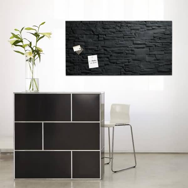 Minimalistisches modernes Interieur mit einem Schrank mit schwarzer Front, der eine Vase mit weißen Blüten hält, einem weißen Stuhl und einem schwarzen Wandkunstpaneel mit angehefteten Notizen.