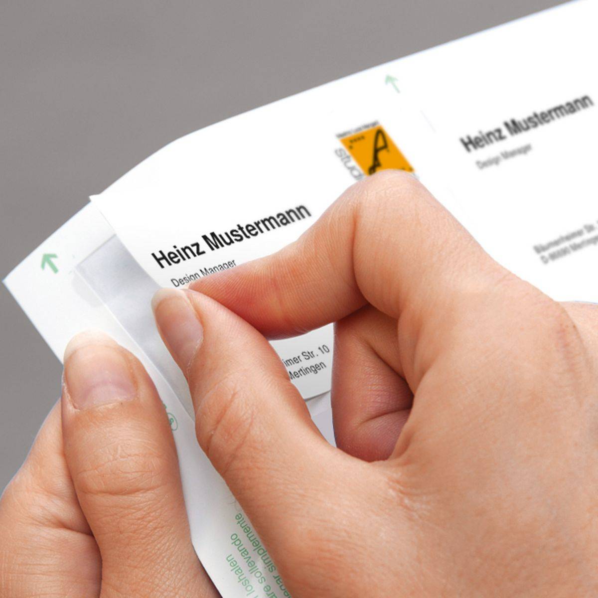 Hände, die einen transparenten Aufkleber von einer Visitenkarte mit der Aufschrift 