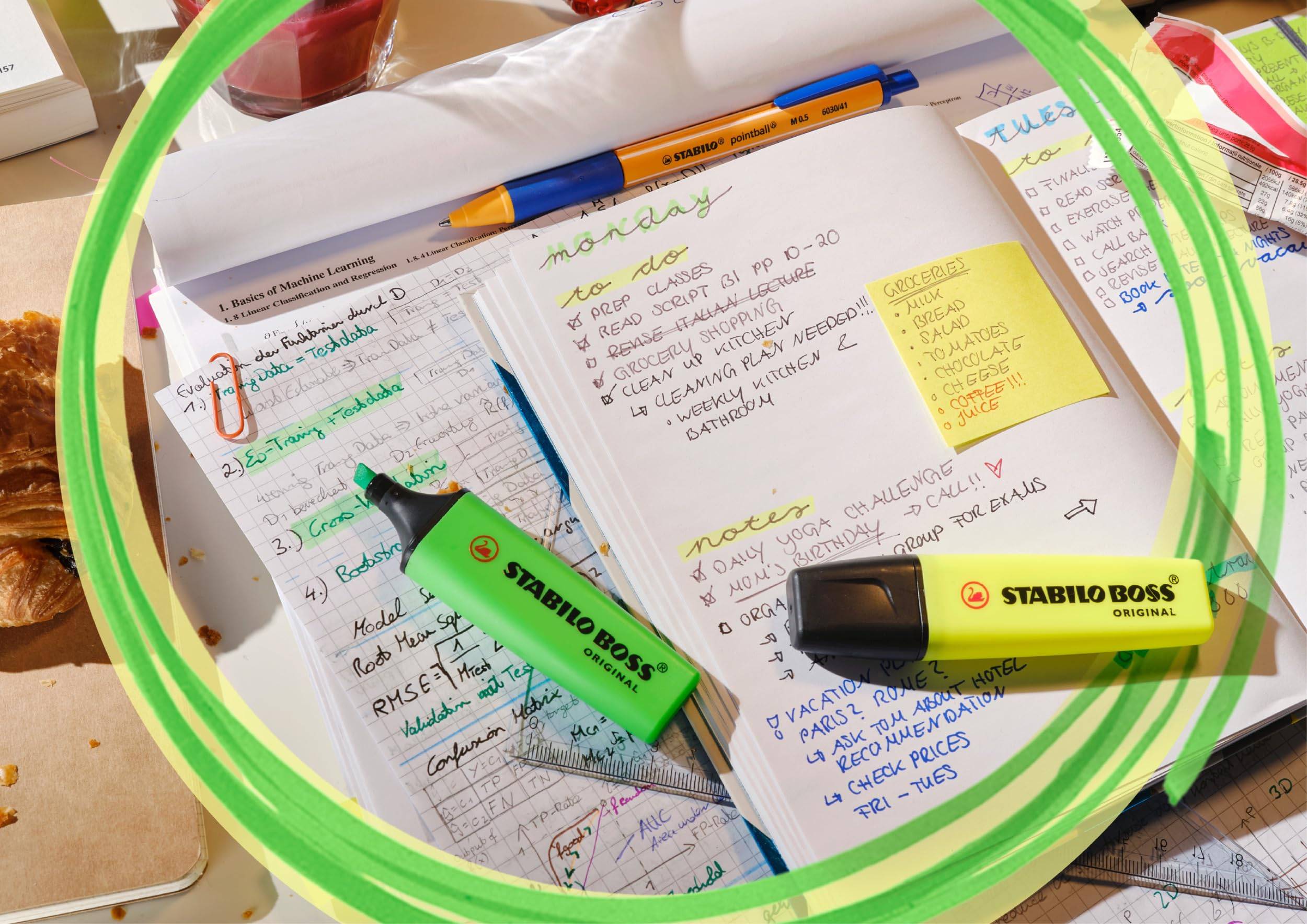 Draufsicht auf ein offenes, stark kommentiertes Notizbuch mit Klebenotizen, Stift und STABILO-Textmarkern in einem leuchtend grünen Rahmen.