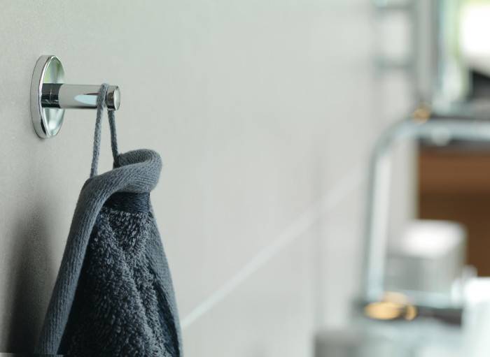 Ein dunkelgraues Handtuch hängt an einem verchromten Wandhaken im Badezimmer.