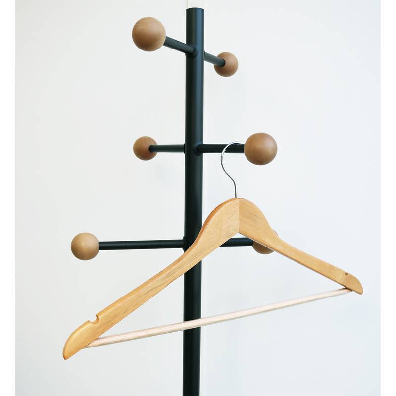 Eine schwarze Garderobe mit Holzknöpfen hält einen einzelnen Holzbügel vor einem schlichten weißen Hintergrund.