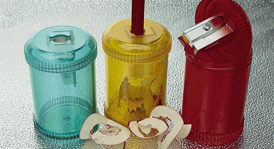 Drei durchscheinende zylindrische Behälter mit Deckel in Blau, Gelb und Rot, mit kleinen dekorativen herzförmigen Ornamenten davor.