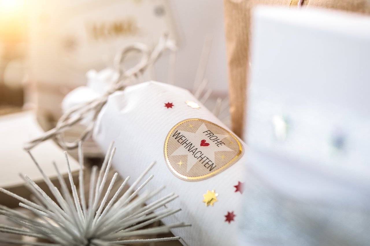 Weiße Weihnachtsknaller mit goldenem Herz-Etikett mit der Aufschrift „Frohe Weihnachten