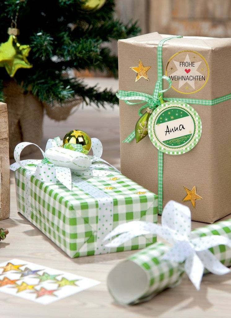 Verpackte Weihnachtsgeschenke auf einem Tisch, darunter ein braunes Geschenk mit der Aufschrift „Frohe Weihnachten