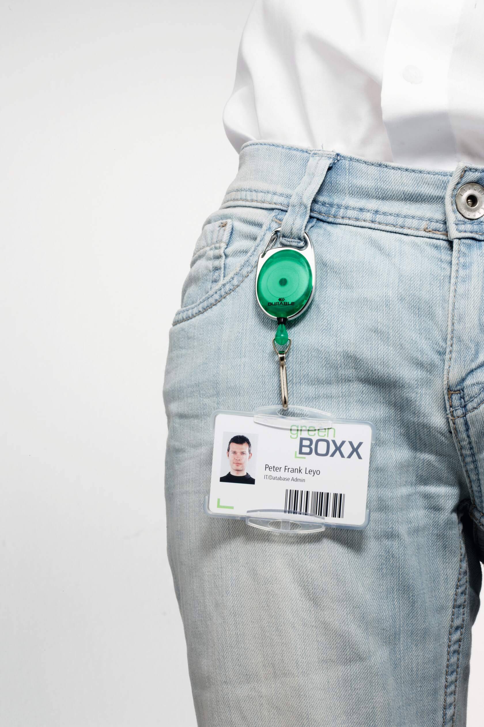 Nahaufnahme einer Person, die hellblaue Jeans trägt, mit einem befestigten Ausweisabzeichen und einer ausziehbaren Halterung am Bund.