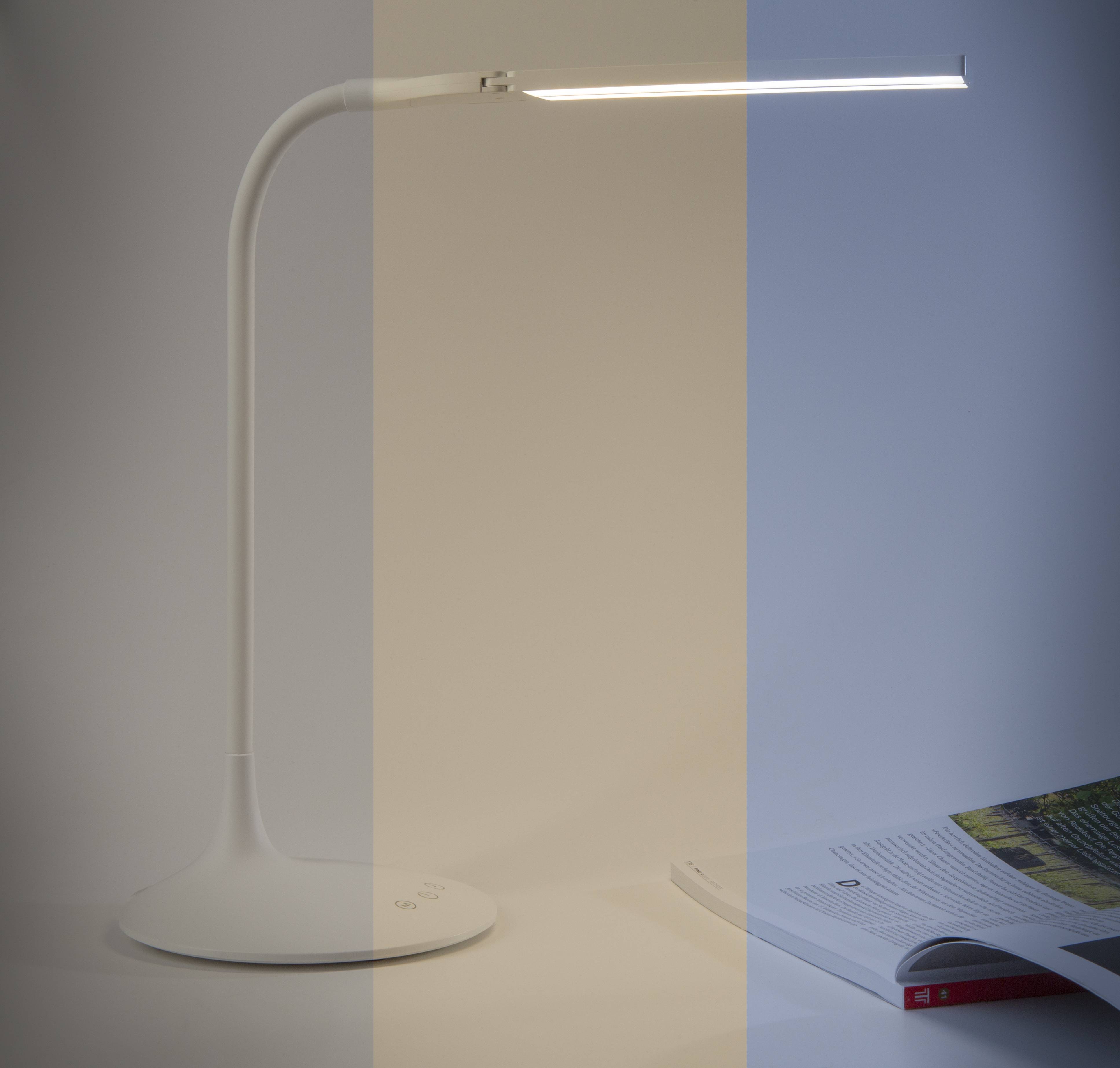 Minimalistische weiße LED-Schreibtischlampe mit geschwungenem Schaft und flacher Basis neben einem aufgeschlagenen Magazin auf weißer Oberfläche