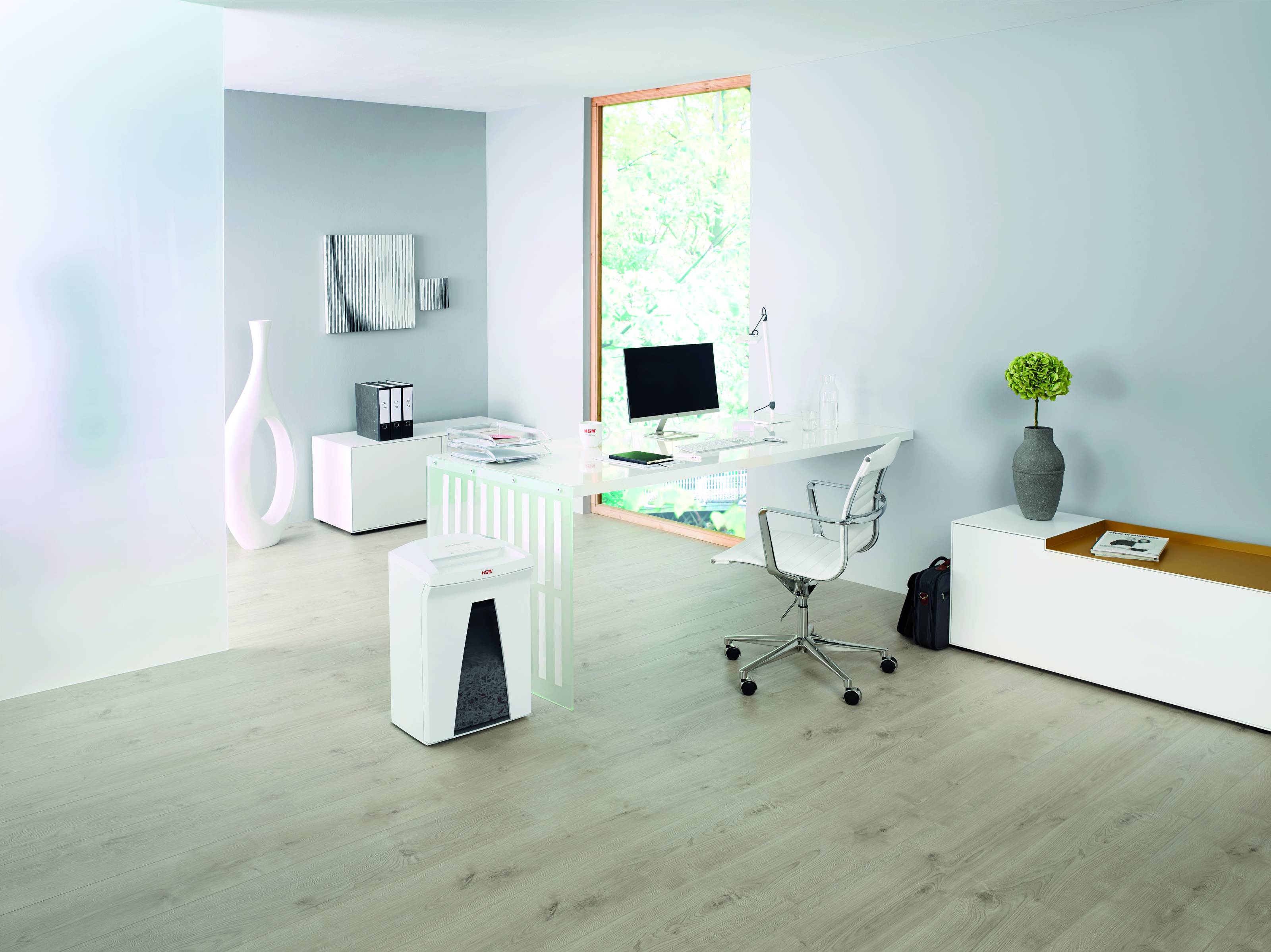 Minimalistisches modernes Büro mit Glastisch, Drehstuhl, kleinen Lagerelementen, Wandkunst und einer Blumenvase in einem hell weißen Raum.