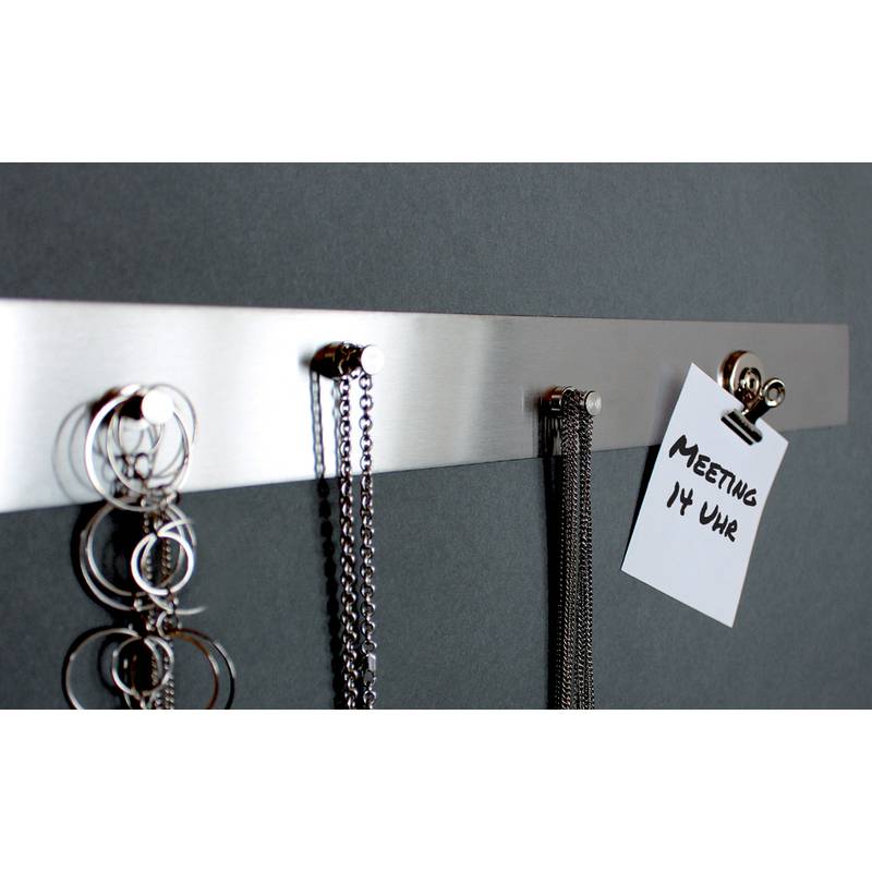 Metallwand-Organizer mit Haken, an denen Schlüsselanhänger, Halsketten und ein angehefteter Zettel mit der Aufschrift „MEETING 14 UHR