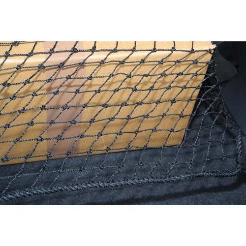 Nahaufnahme einer Rückseite eines Autositzes, bedeckt mit einem schwarzen Gepäcknetz, das die beige Polsterung dahinter zeigt.