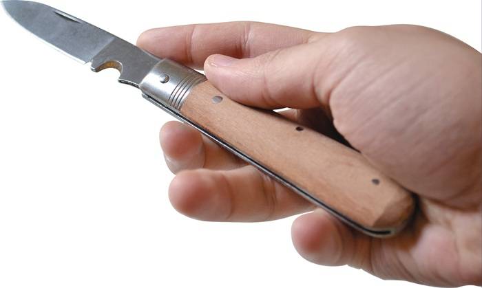 Eine Hand, die ein zusammenklappbares Taschenmesser mit einem Holzgriff hält, mit einer halb geöffneten Klinge aus Edelstahl.