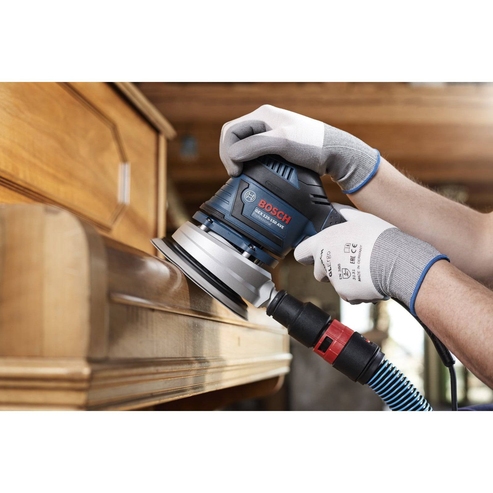 Eine Person verwendet eine elektrische Schleifmaschine, um die Seite eines Holztisches zu glätten und dabei die Holzbearbeitung in Aktion zu zeigen.