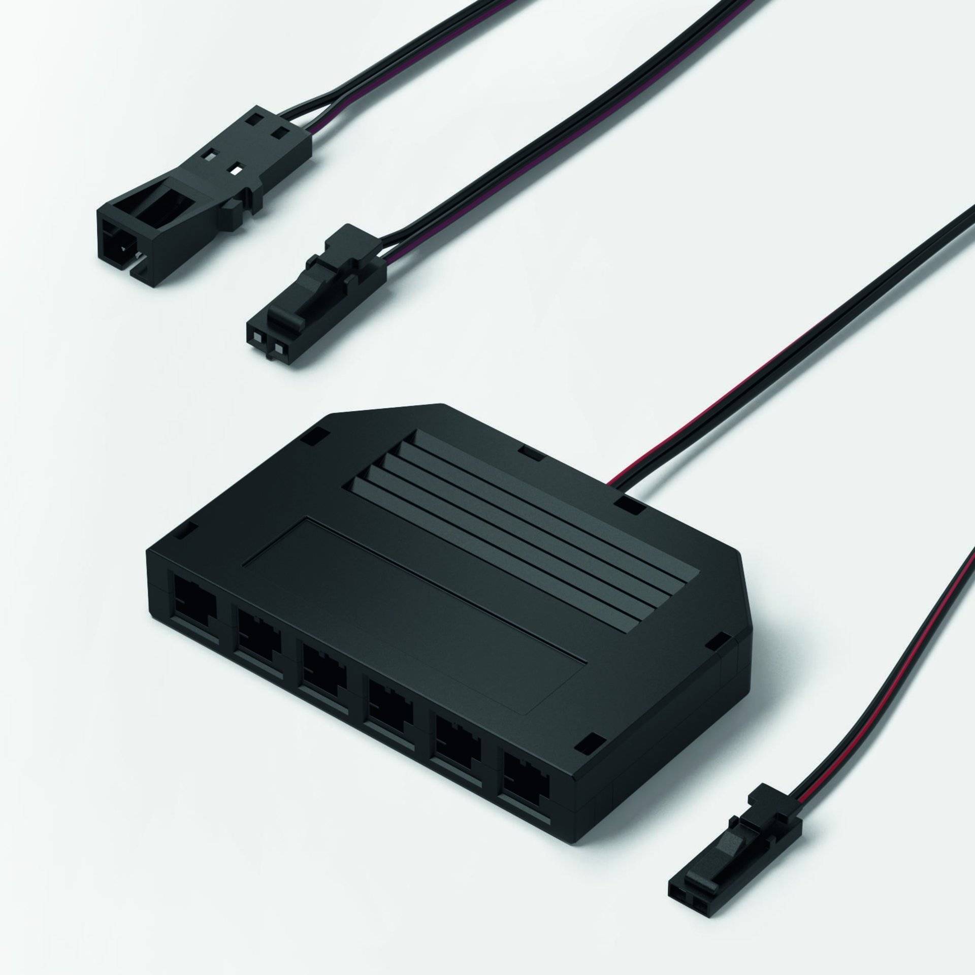 Ein schwarzer Computer- oder Elektronik-Verbindungshub mit mehreren Anschlüssen und angeschlossenen Kabeln, entwickelt zur Strom- oder Datenverteilung.