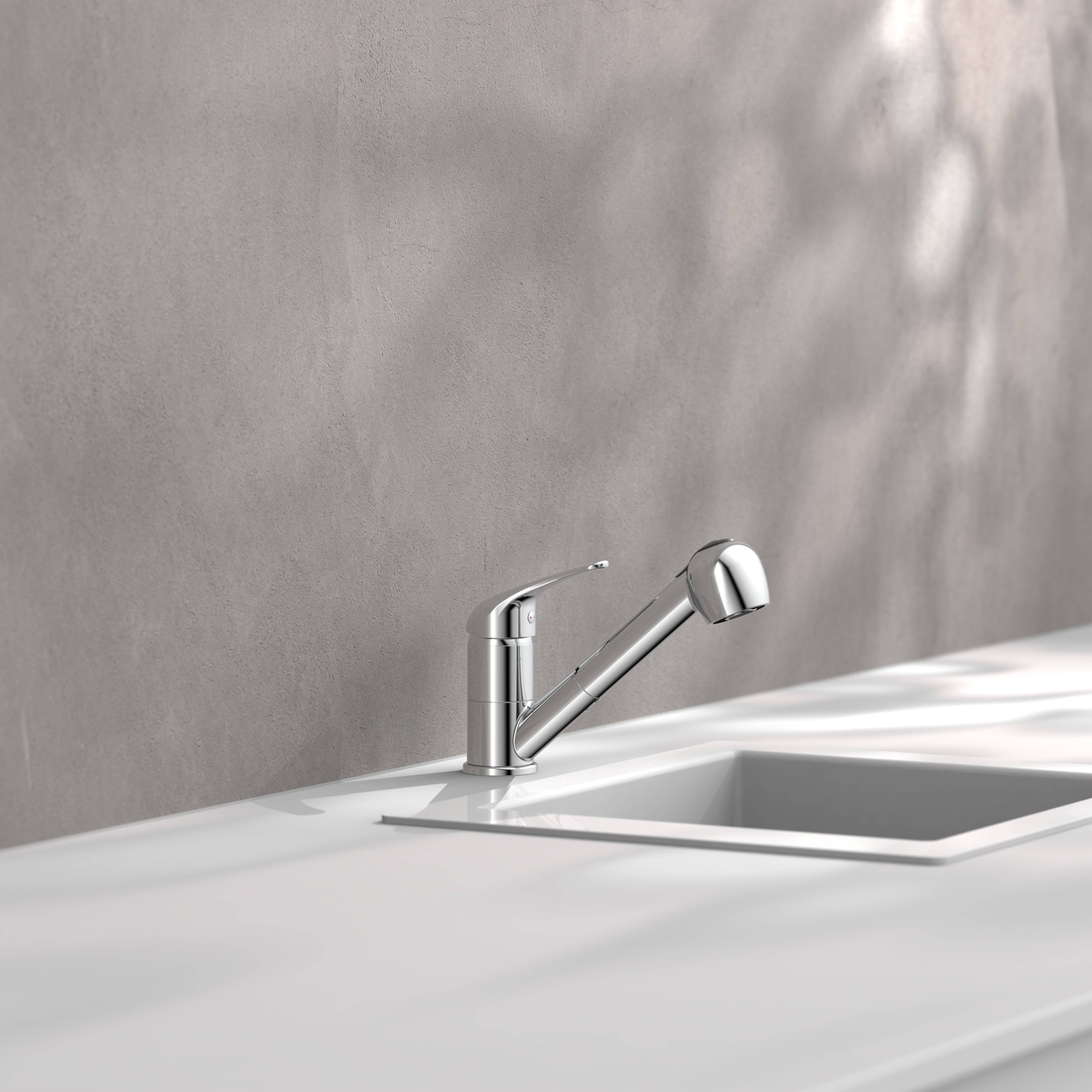 Ein schlanker verchromter Wasserhahn in einer weißen Arbeitsplatte neben einem rechteckigen Spülbecken mit grauem Wandhintergrund.