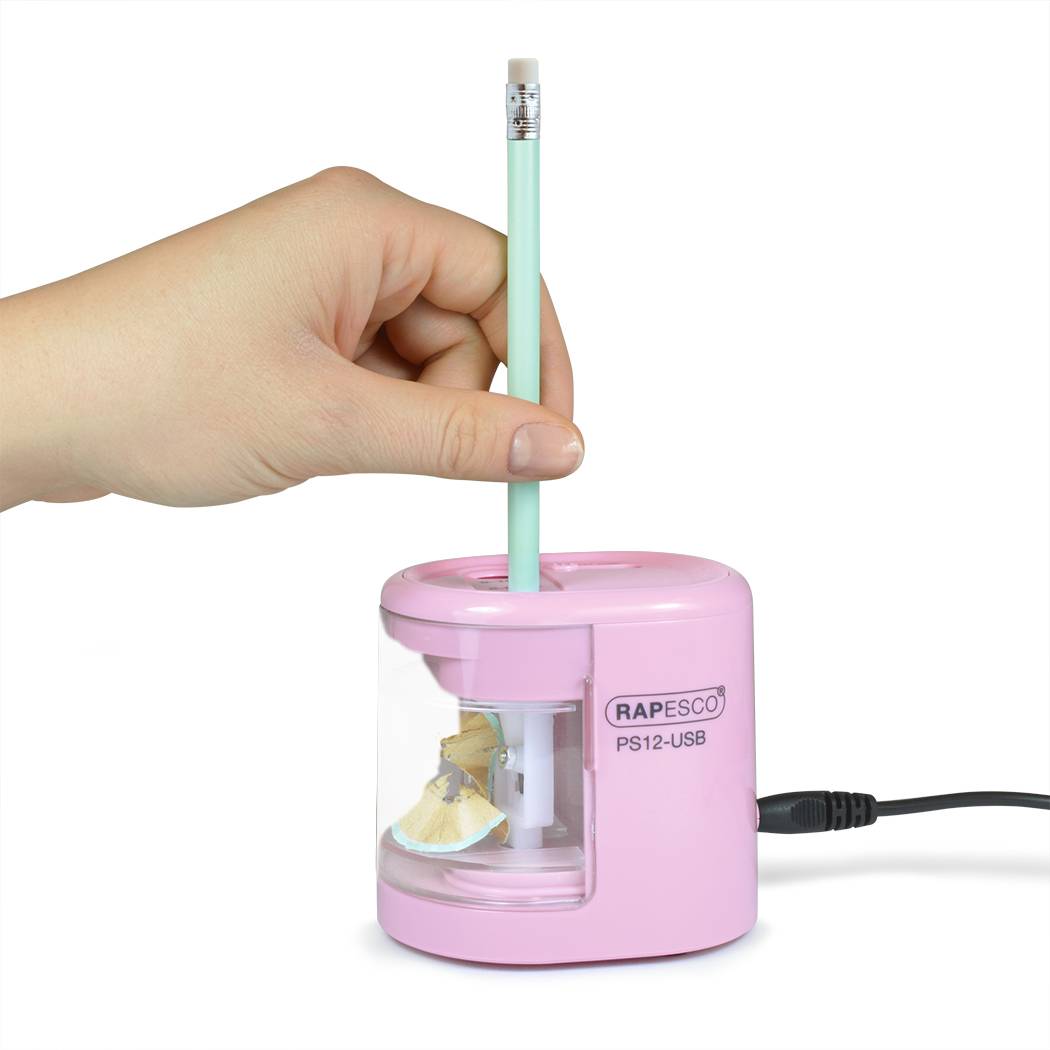 Einen Bleistift von Hand in einem rosa elektrischen Bleistiftspitzer mit der Bezeichnung "RAPESCO PS12-USB"" anspitzen, an dem ein USB-Stromkabel angeschlossen ist.