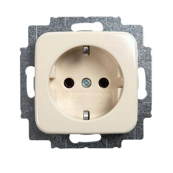 Eine weiße Steckdose mit zwei runden Löchern und einem Erdungsbolzenloch, montiert auf einem Metallrahmen, mit der Markenbezeichnung 'Busch-Jaeger'.