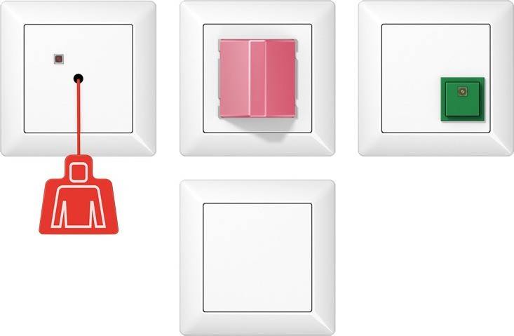 Eine Reihe von vier weißen Wandschaltern, einer in Rosa, auf weißem Hintergrund.