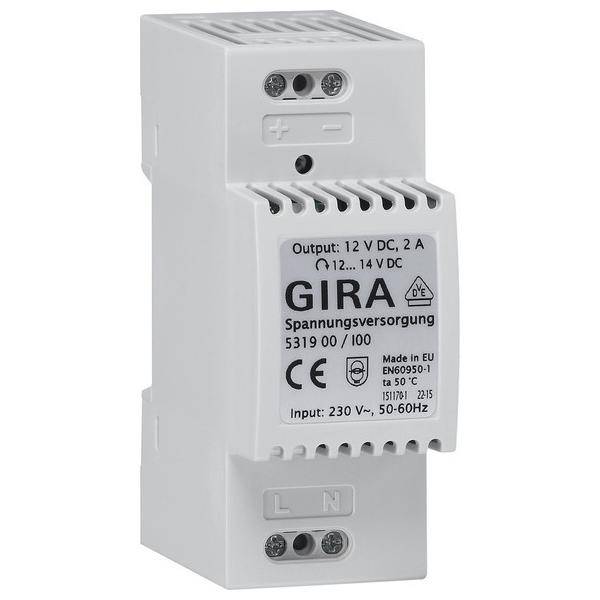 Ein weißes Elektrogerät mit der Beschriftung 'GIRA Spannungsversorgung' mit Ausgangsspezifikationen von 12V DC, 2A und Eingangsspannung von 230V AC.