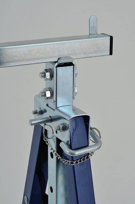 Nahaufnahme einer Metallanhängerkupplungskupplung mit Sicherungskette und blauem Riegel auf grauem Hintergrund.