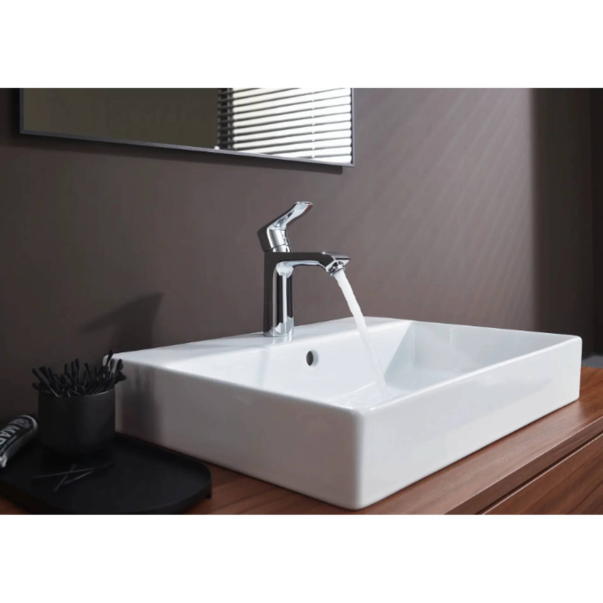 Modernes Badezimmerbecken mit Chromarmatur, aus der Wasser läuft, auf einem Holzwaschtisch, mit Spiegel und Jalousien darüber.