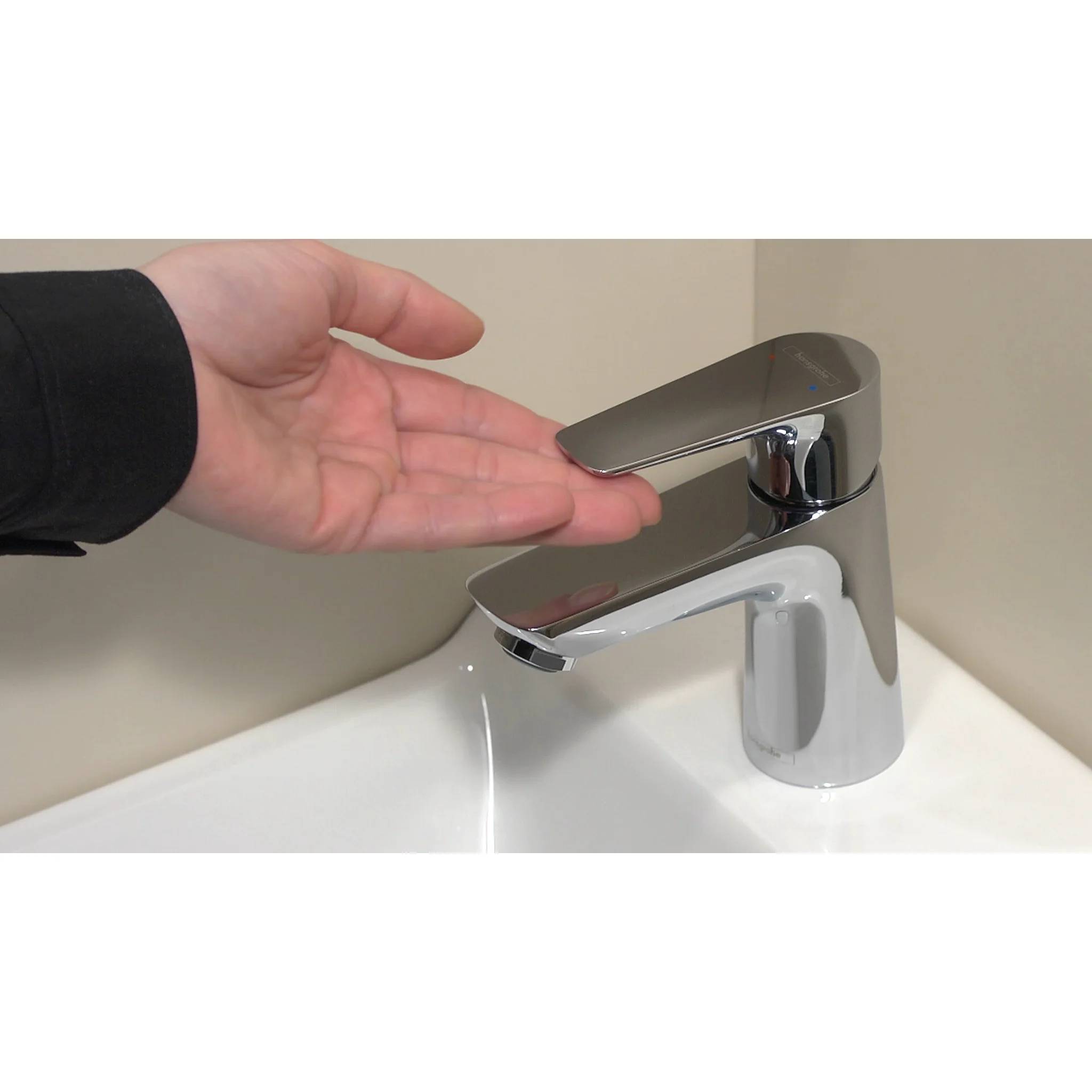Hand unter einem modernen Badezimmer-Sensor-Wasserhahn, der ein berührungsloses Wasserhahn zum Händewaschen zeigt.